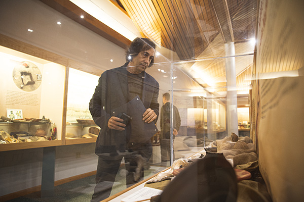 UWF archaeology museum guest looking at artifacts in a display case.