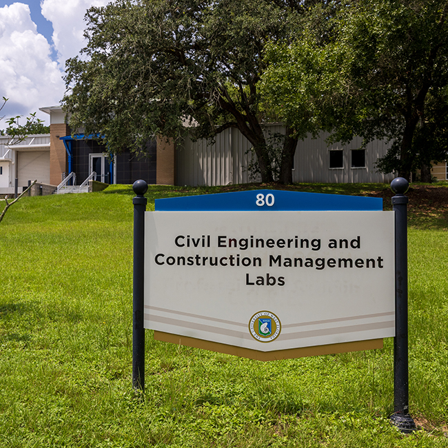Building 80 Civil Engineering and Construction Management Labs sign in front of the building and a large tree.
