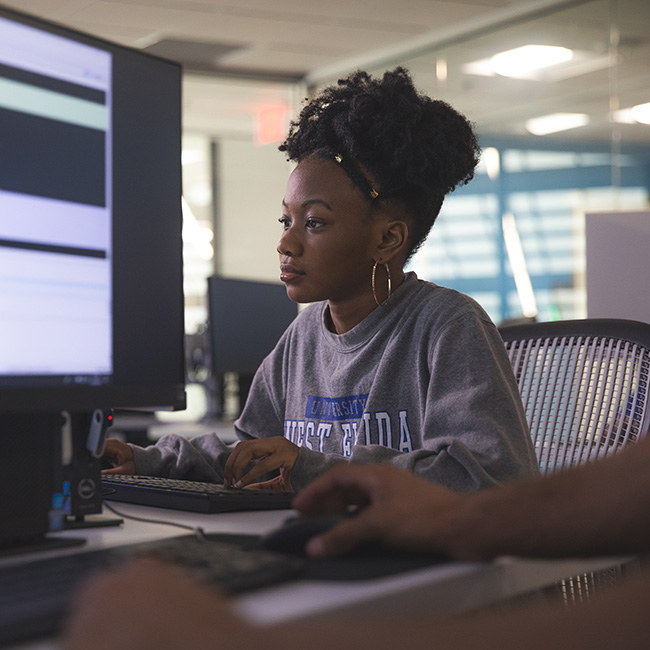 A student using a computer with a screen of a different computer monitor present in the foreground.