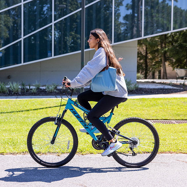 A student riding a bicycle on a paved road.