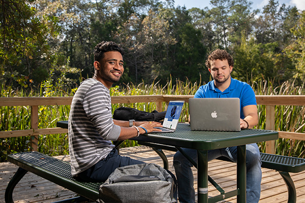 Two students working outside on laptops