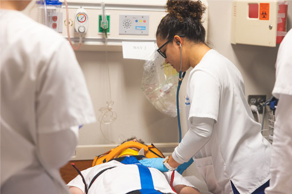 Nursing student assisting a simulated patient.