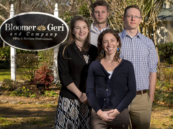four members of the bloomer geri accounting firm posing by their sign