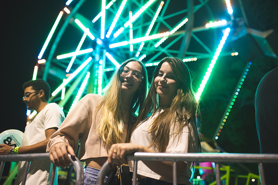 Two students pose in front of a lighted Ferris Wheel during CAB After Dark