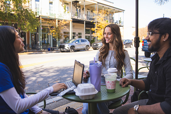 Three Argos gather with laptops and coffee shop beverages on Palafox in downtown Pensacola.