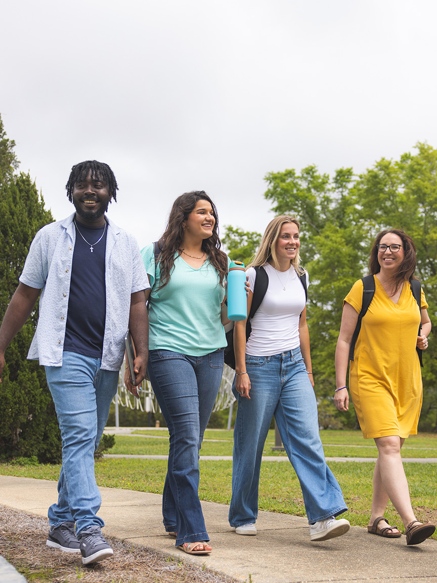 Four students walk together outside the Center for Fine and Performing Arts.