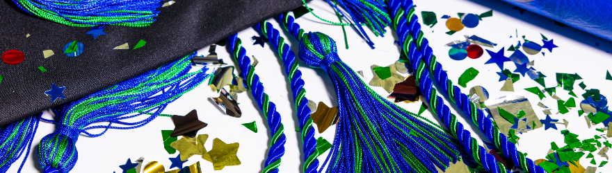 The blue and green Philanthropy Cord lays next to a black grad cap and confetti.