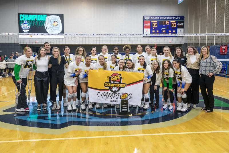 The 2023 Volleyball team poses with the GSC trophy and banner.