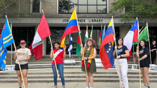 Students stand in front of Pace Library holding various flags of countries in Central and South America.