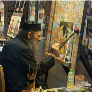 A Greek Orthodox Priest paints a gold foiled Byzantine icon in his studio in Greece.
