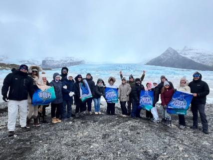 Argos pose for a group photo on a rocks next to a glacier.