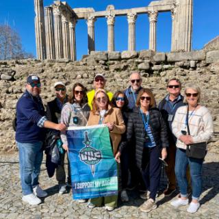 Group of Argos with UWF flag pose in front of ruins in Portugal.
