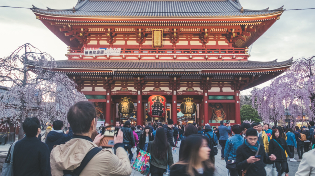 Tourists in front of the busy red Asakusa Kannon Temple in Tokyo Japan