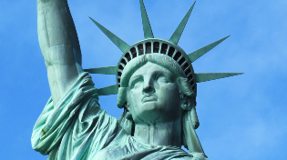 Upper bust of the Green New York City Statue of Liberty with the blue sky in the background