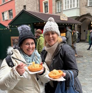 Two women enjoy German food outside in a market