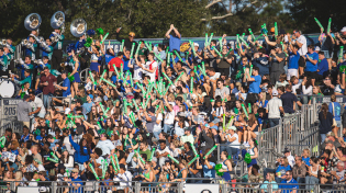 A crowd of Argo fans fills the bleachers at PenAir Field during a football game.