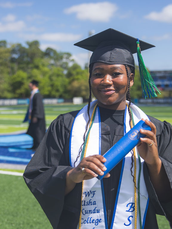 Student in a graduation cap and gown holding a diploma case