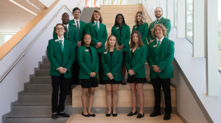 a group of student ambassadors pose together in their green jackets for a formal photo