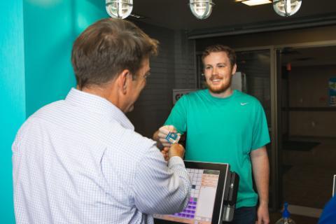 An alumnus hands his Nautilus Card to a UWF employee at the Nautilus Market.