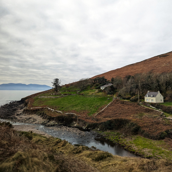 A small cottage sits on a hill on a bluff in Ireland