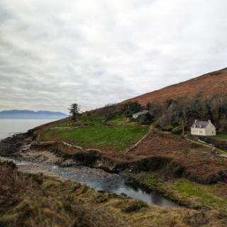 A small cottage sits on a hill on a bluff in Ireland