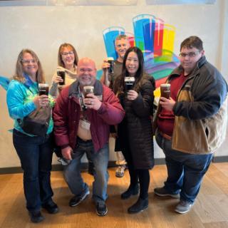 A group of alumni pose with pints of Guinness beer.
