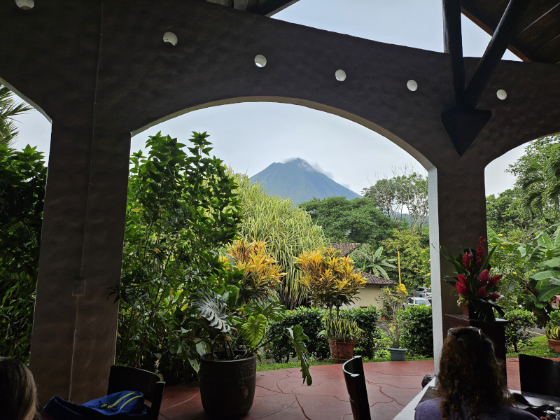 The view from a patio in Costa Rica includes a lush jungle and volcano in the distance.