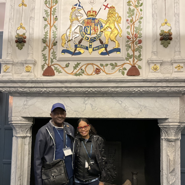 two travelers pose in front of a medieval fireplace