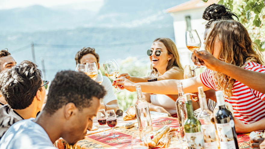 A group of young travelers cheers with wine at an outdoor table.