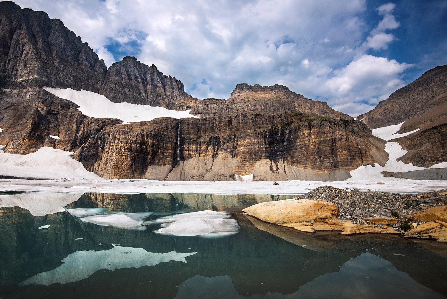 Snowy mountains on a body of water in Glacier National Park