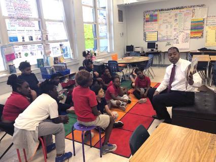 Harrison Peters reading a book to a classroom of children