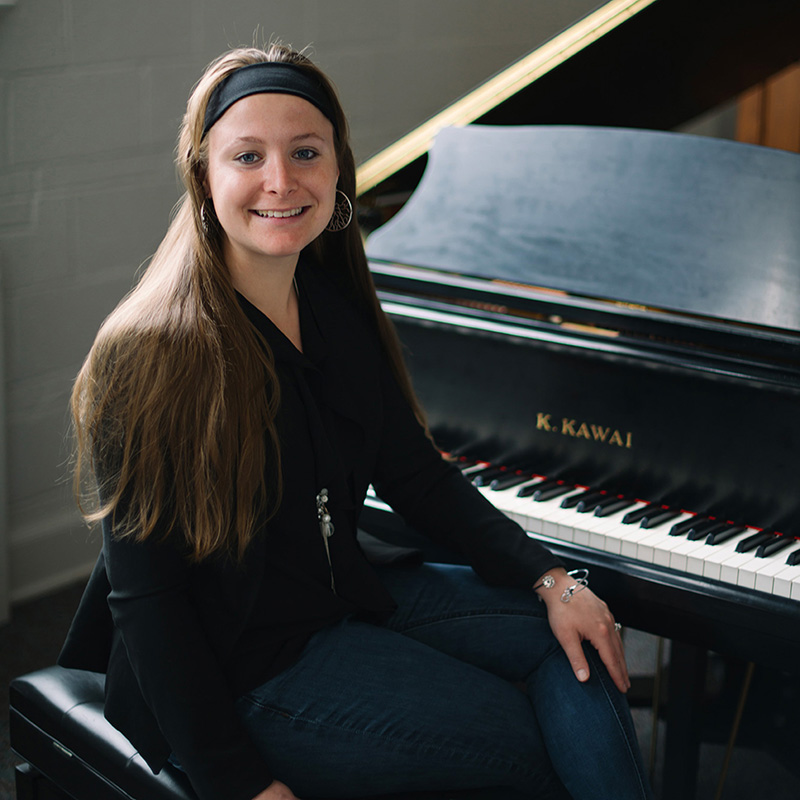 Dr. Patricia Izbicki seated at a grand piano