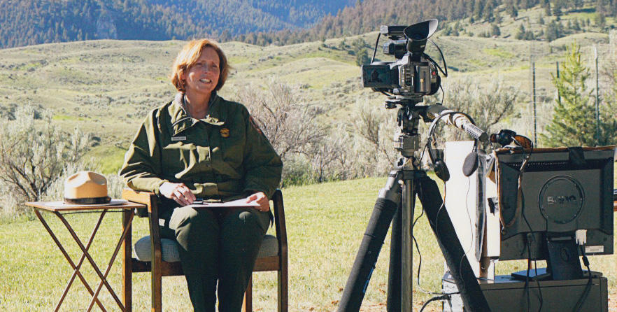 Suzanne Lewis seated for a TV interview in Yellowstone National Park