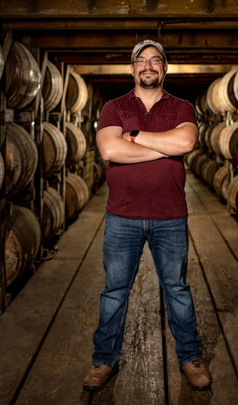 Nicolas Laracuente surrounded by bourbon barrels