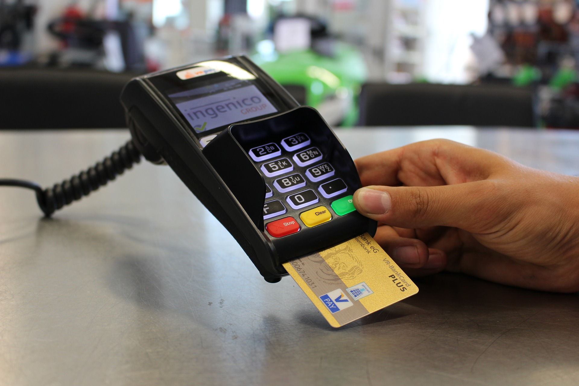 A hand holding a credit card chip reader payment device with a card inserted.
