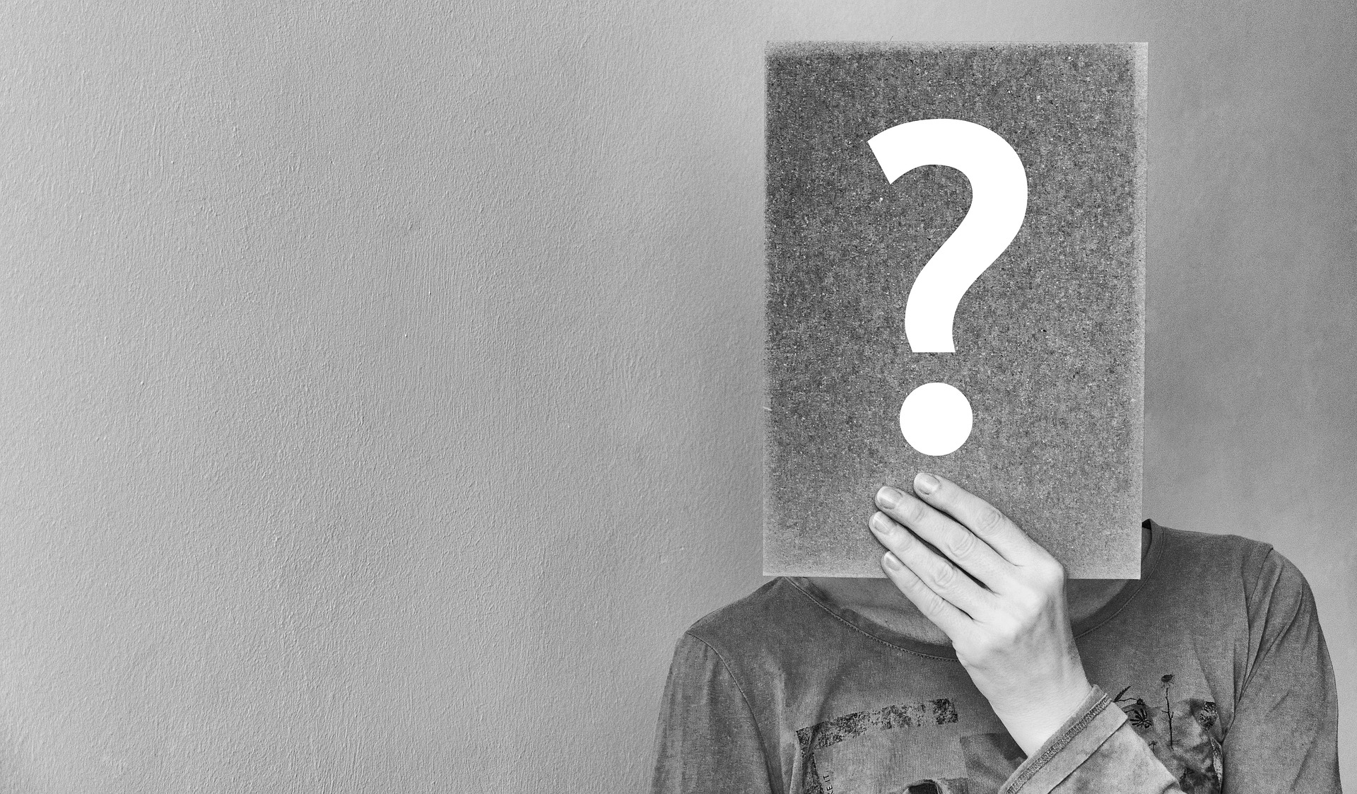 Person holding a question mark in front of face