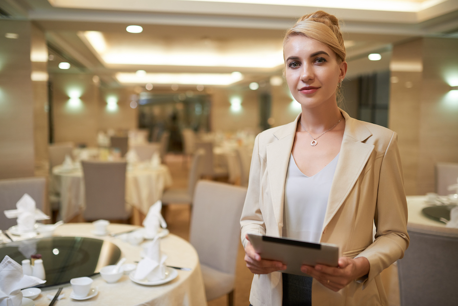 Corporate event planner holding a tablet and standing in event space