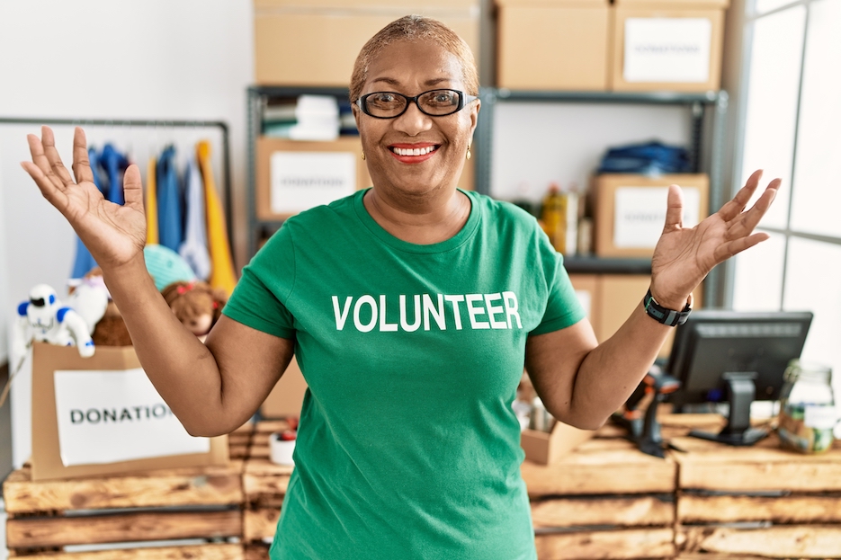 Smiling senior volunteer wearing a green shirt giving a double thumbs up
