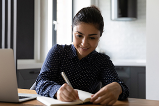 Business women watching lecture online and taking notes