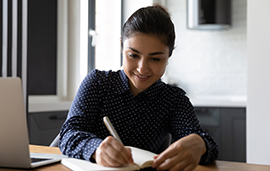 Business women watching lecture online and taking notes