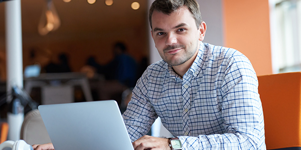 Smiling male employee with laptop at desk