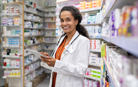 Pharmacy technician holding clipboard inventorying prescriptions