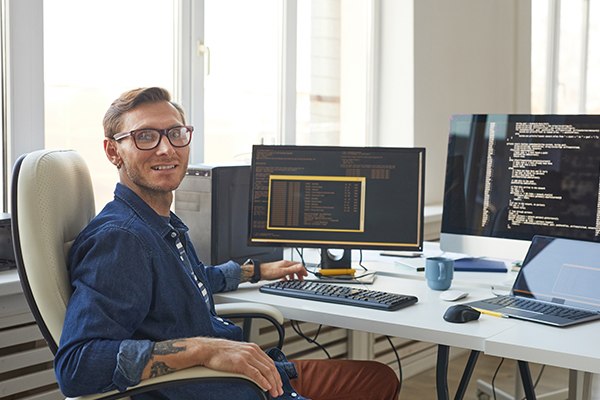 Software developer at desk smiling at camera
