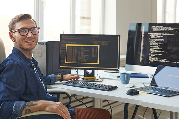 Software developer at desk smiling at camera
