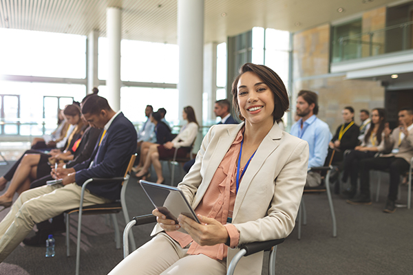 Conference event planner smiling at camera durning a conference session