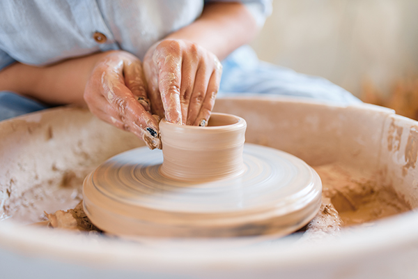 Hands working with clay on pottery wheel