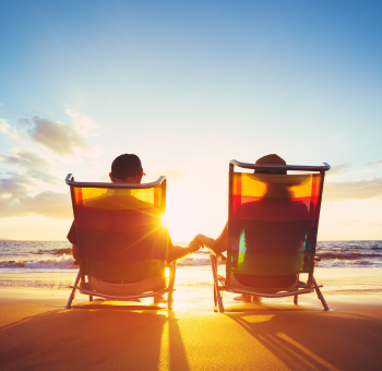 A couple sitting on beach chairs watching the sunset