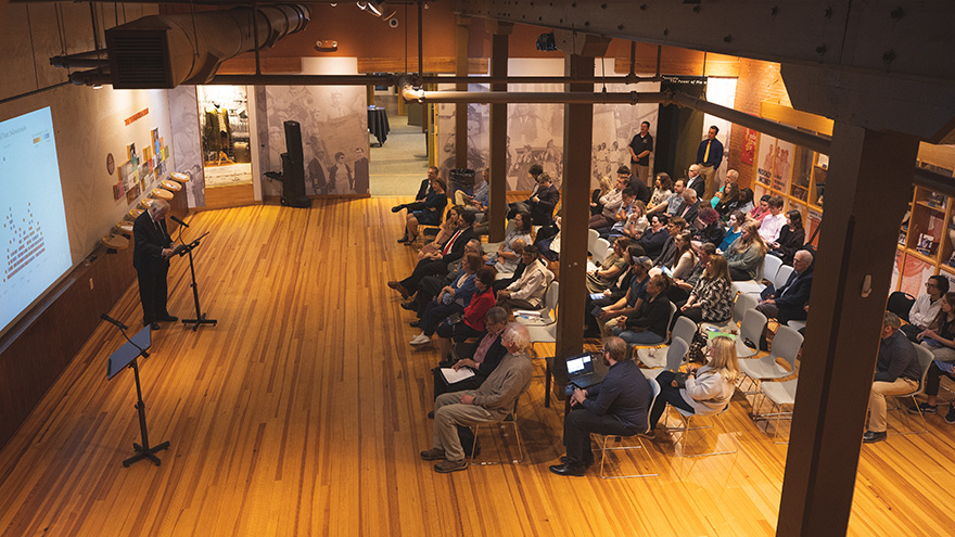 A presenters is giving a lectures to a room of people at Voices of Pensacola.
