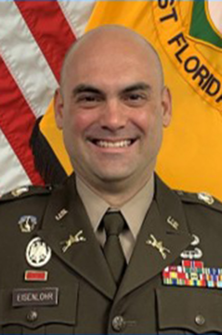 Michael Eisenlohr indoor headshot in military uniform in front of the U.S. flag.