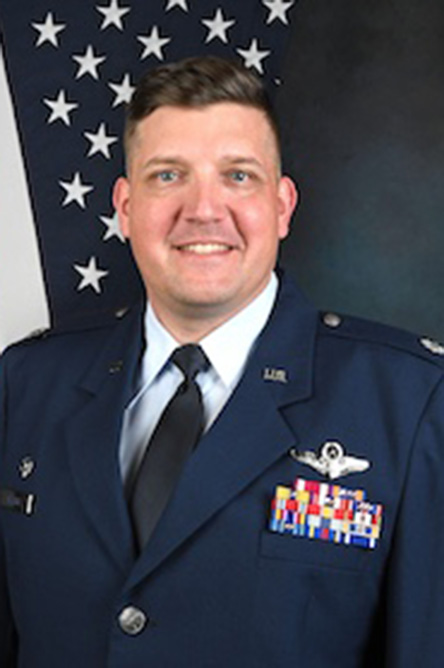 Ross Clark indoor headshot in military uniform in front of the U.S. flag.